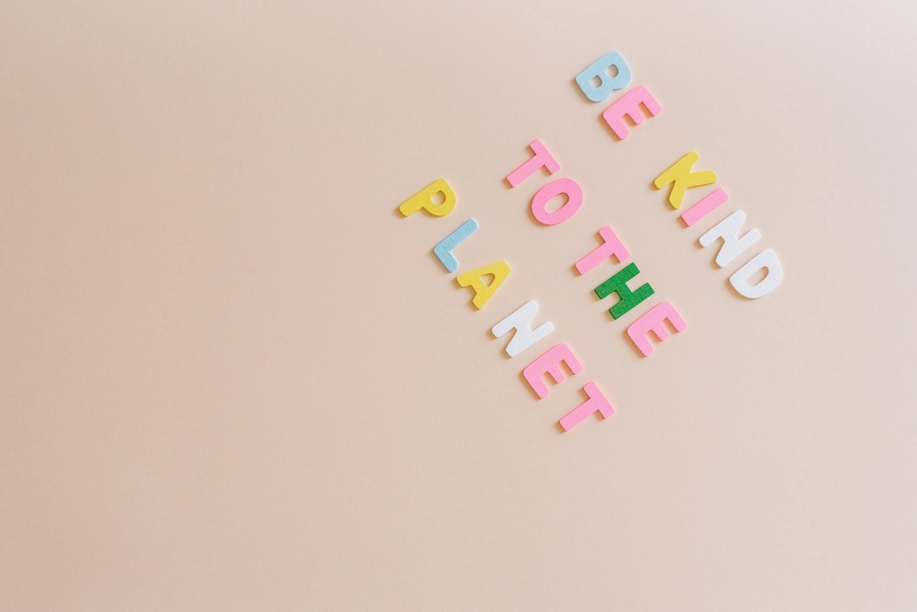 Napis Be kind to the planet na beżowym tle w ekologicznej grafice