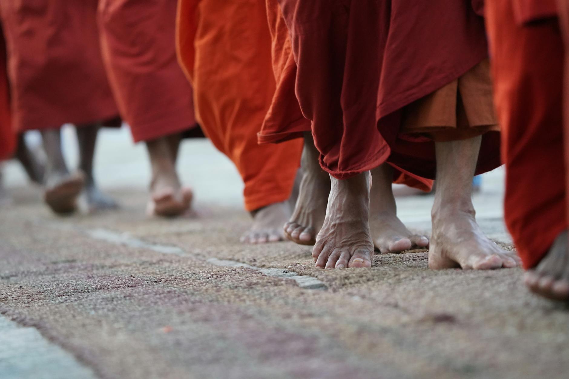 Buddystyczni mnisi boso w pomarańczowych szatach idą w procesji