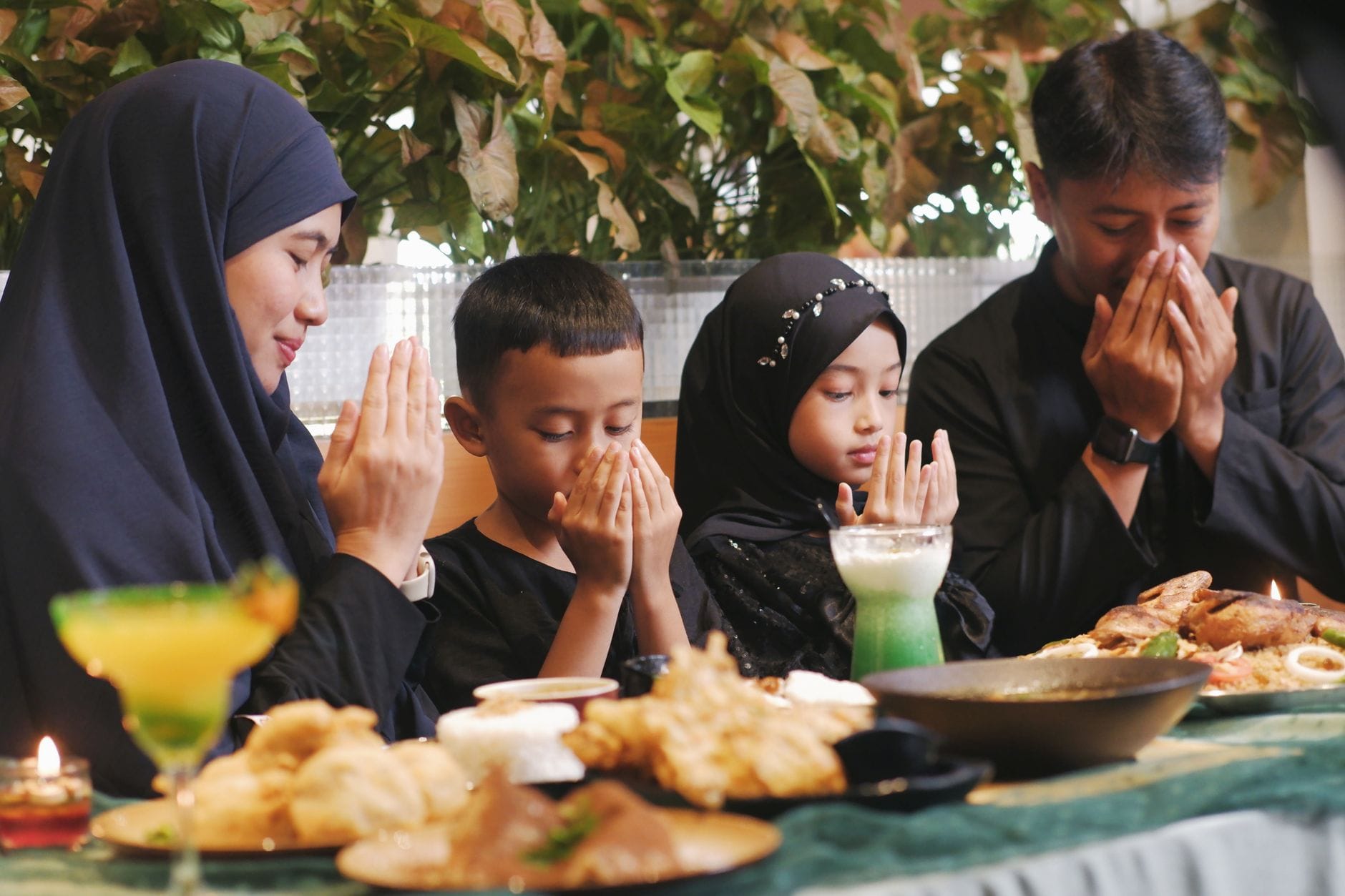 Rodzina modli się przed wspólnym posiłkiem ramadanowym w domu