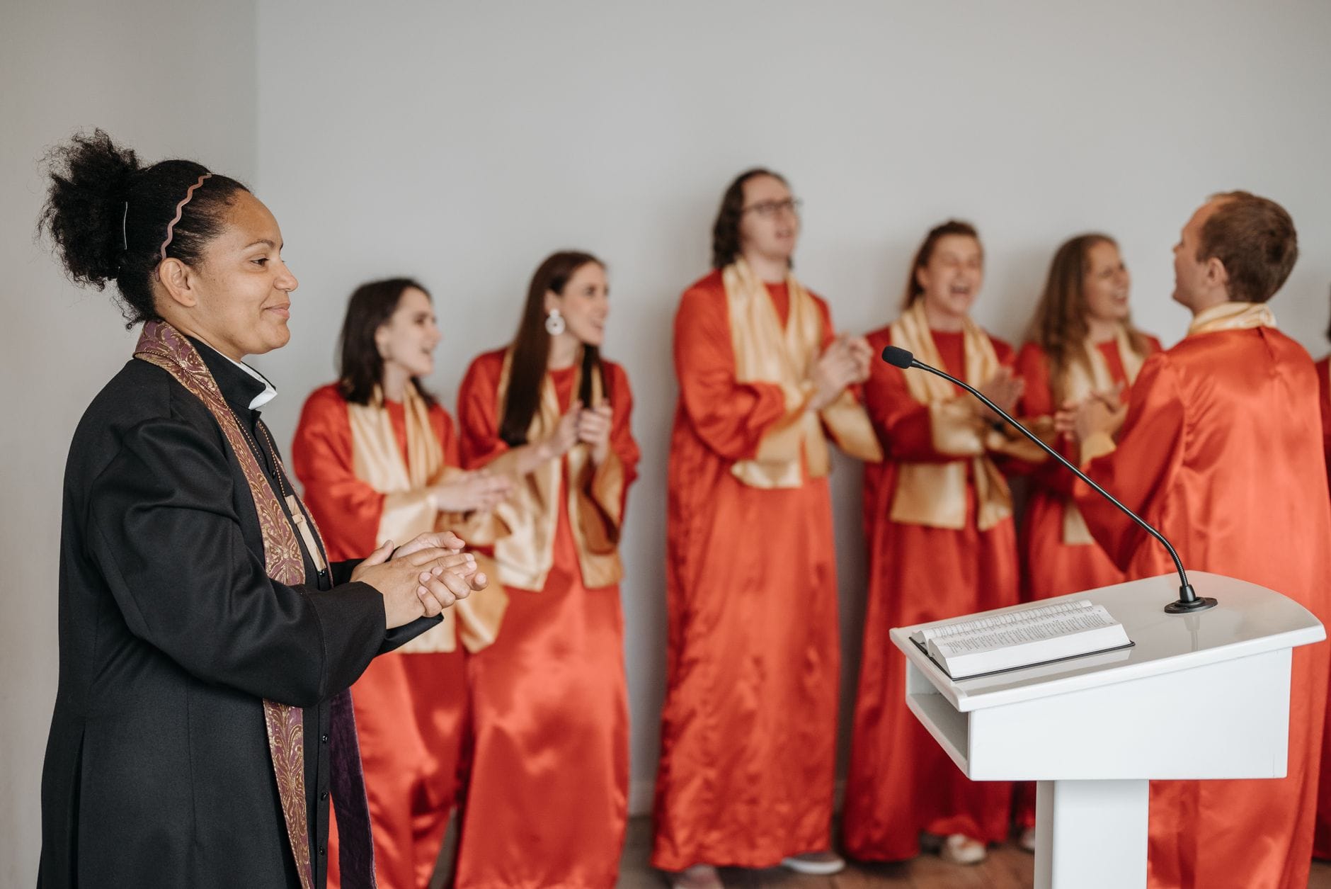 Różnorodny chór śpiewa i klaszcze w kościele prowadzony przez pastorkę Różnorodny chór śpiewa i klaszcze w kościele prowadzony przez pastorkę