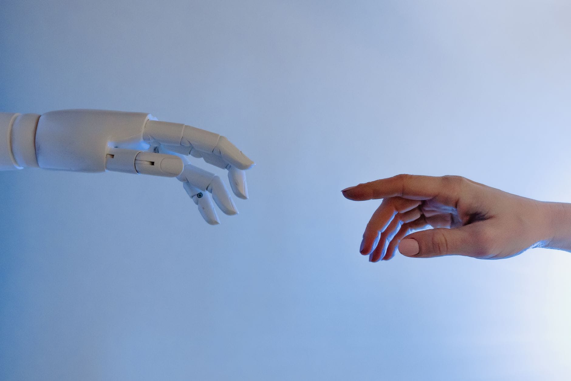 Ludzka dłoń wyciągnięta w stronę robotycznej dłoni